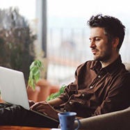 Man sitting out couch typing on laptop.