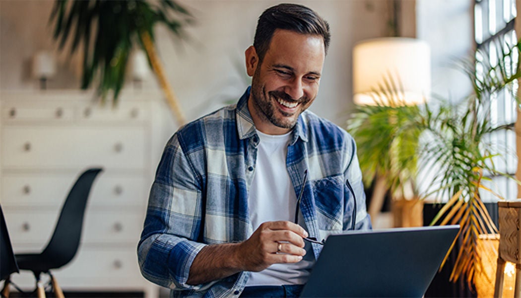 Happy man using his computer at home