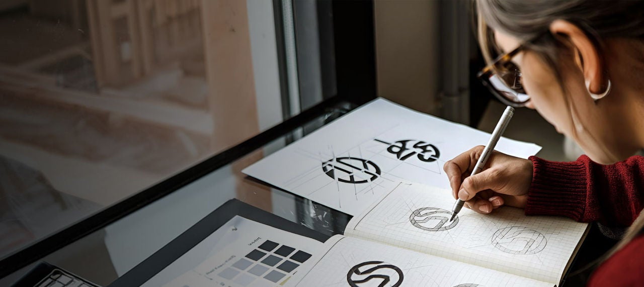 woman drawing logos in a notebook
