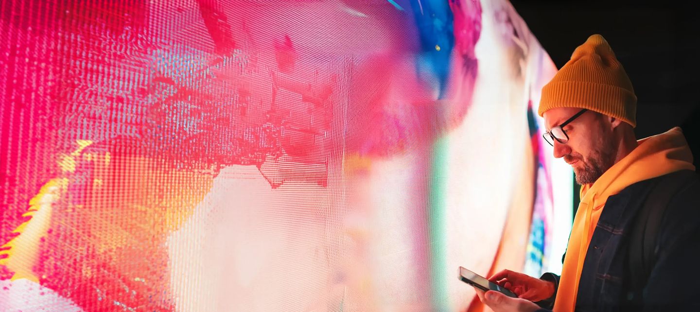 A man in a yellow hat looking at a cellphone 