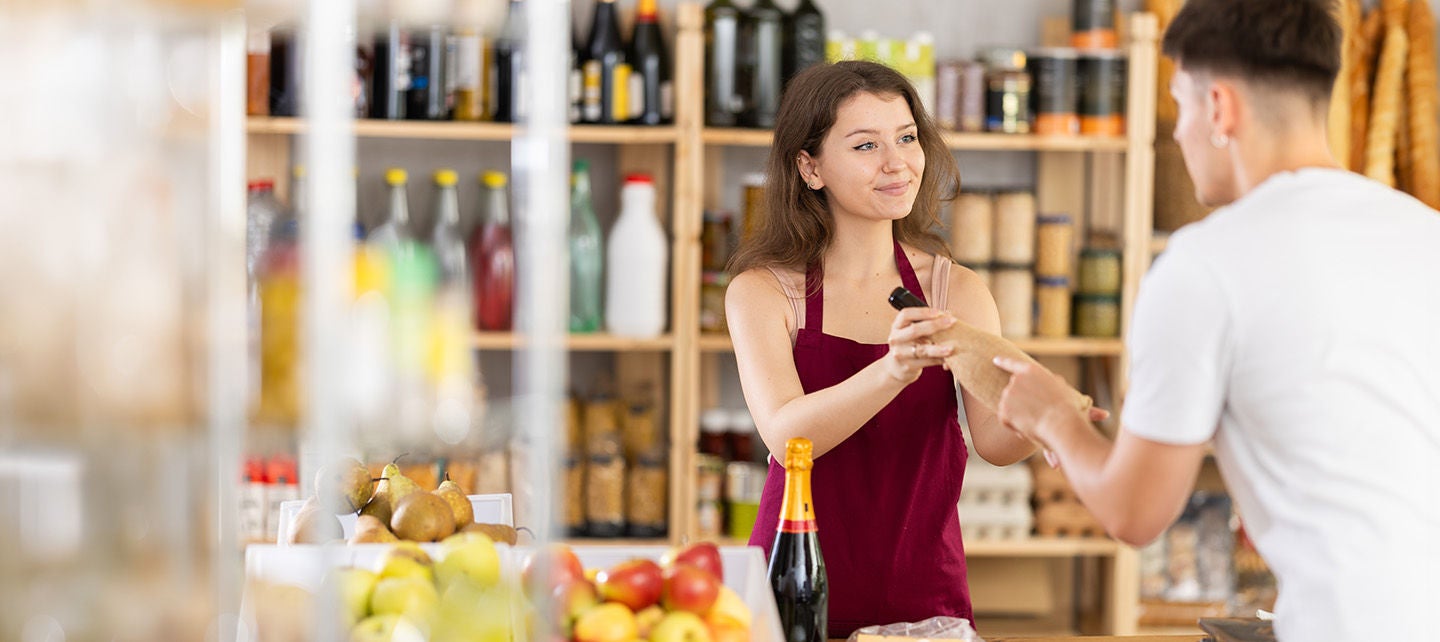 Making more pesonalized shopping experience - a shopkeeper helps customer with bottles
