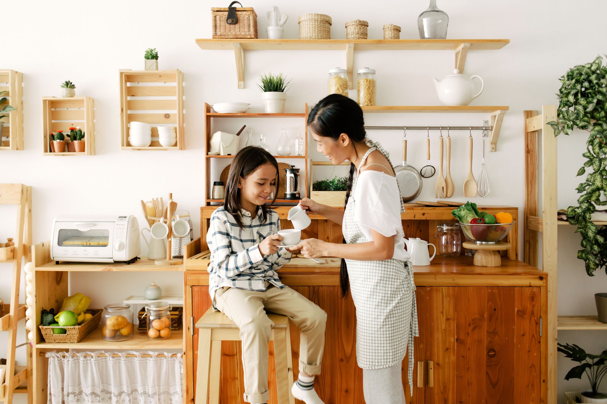 Asian mother and child drinking tea together in the kitchen