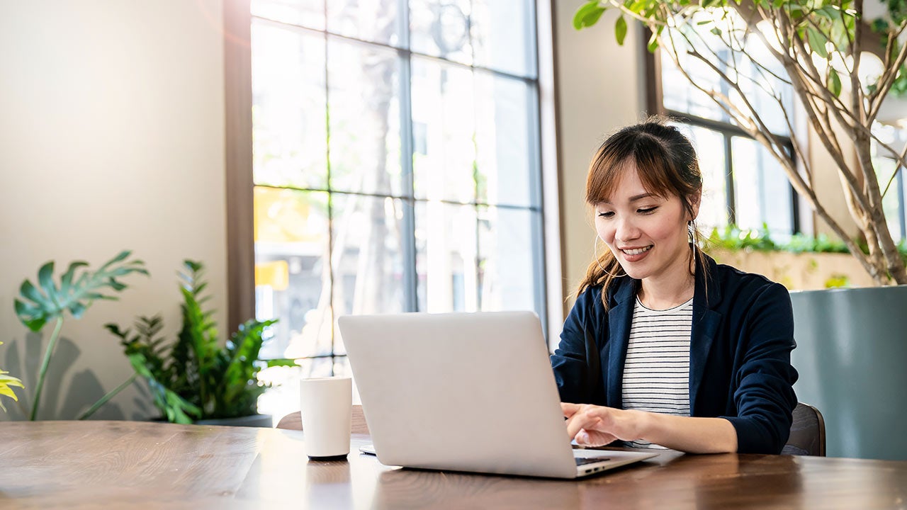 Frau arbeitet am Laptop vor einem Fenster