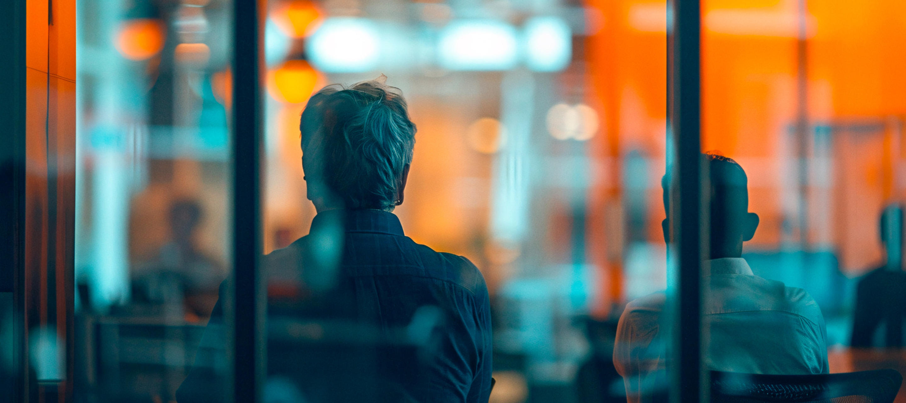 Two men in the office behind glass