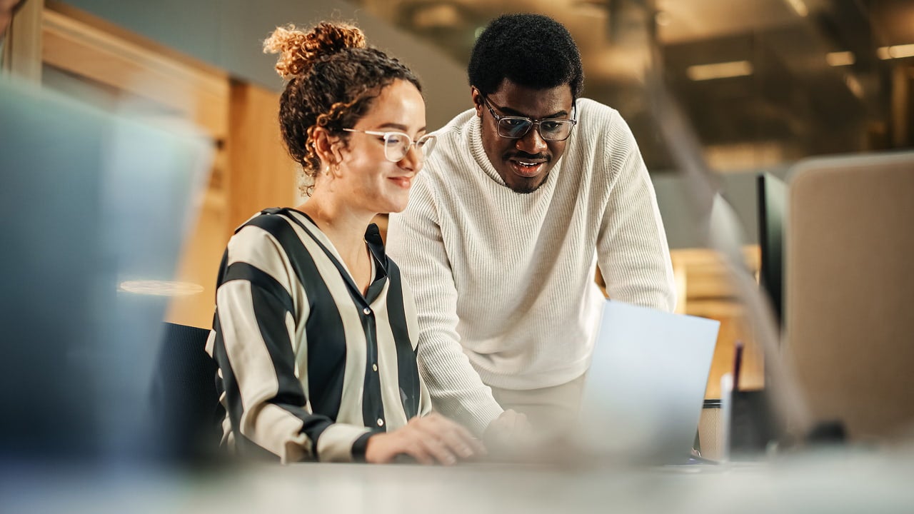 smiling colleagues collaborating on a laptop computer