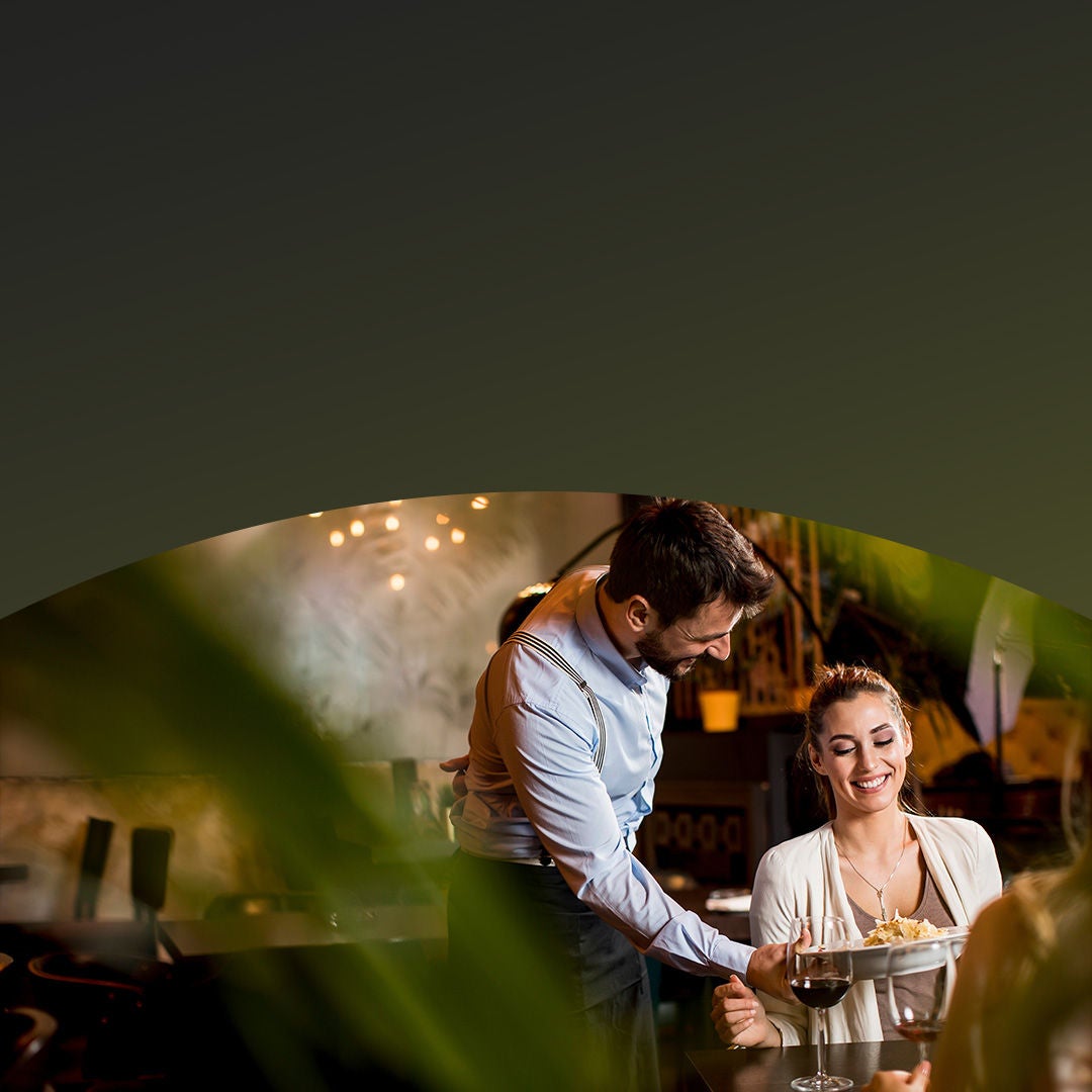 Waiter serving meal to woman sitting