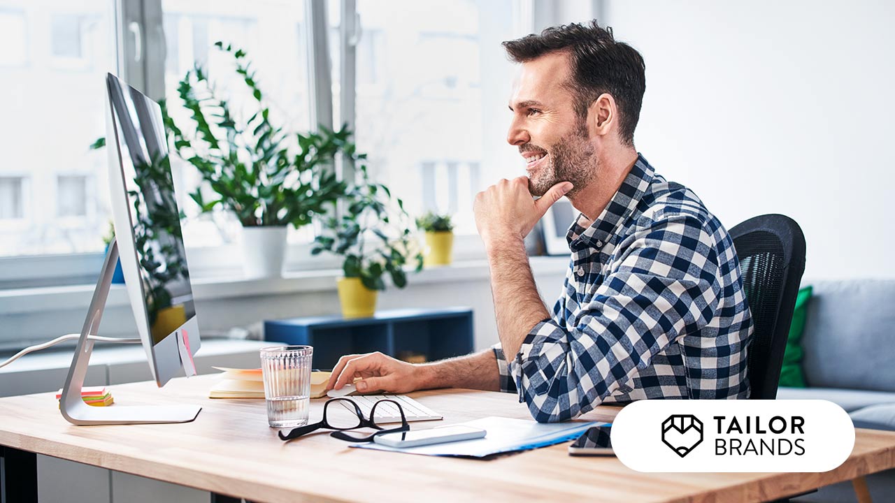 Man working in a bright office. Tailor Brands logo.