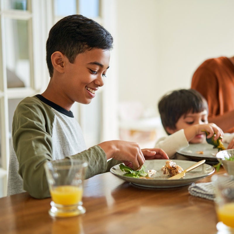 woman holding her hat facing a sunset