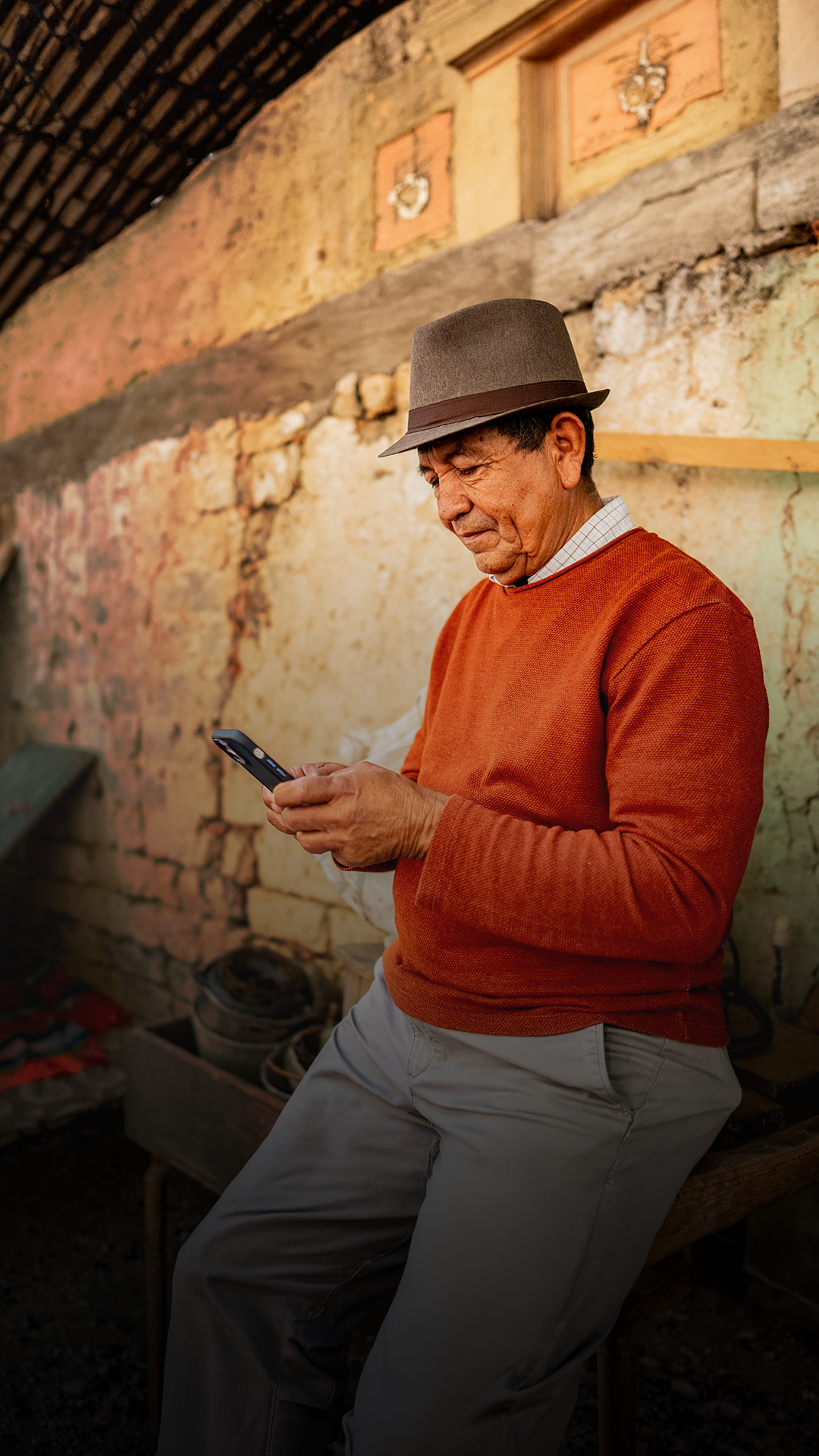 Hombre apoyado en la pared mirando el celular