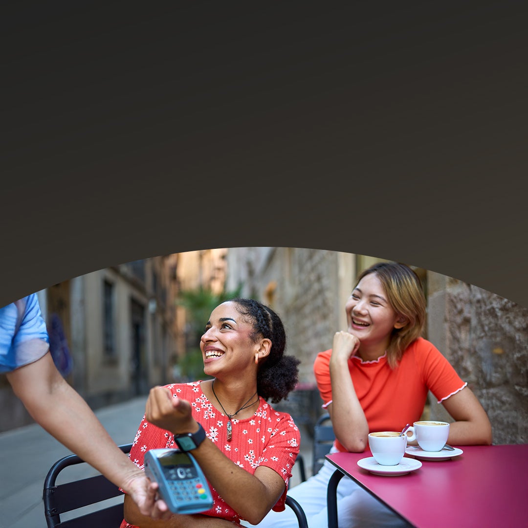 Women paying using smart watch in a cafeteria.