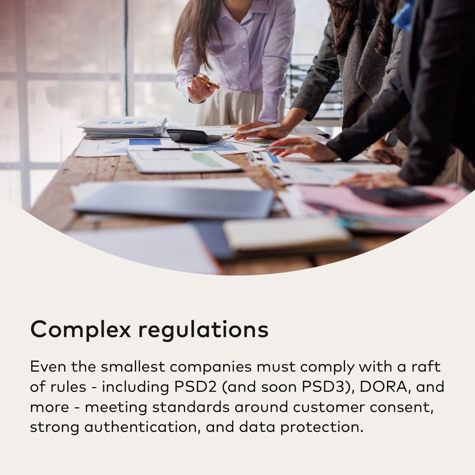 A group of people in business attire discusses documents spread on a wooden table.