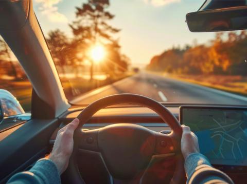 A driver's perspective looking down a highway toward the sunset, symbolizing the forward-looking economic outlook for 2025.
