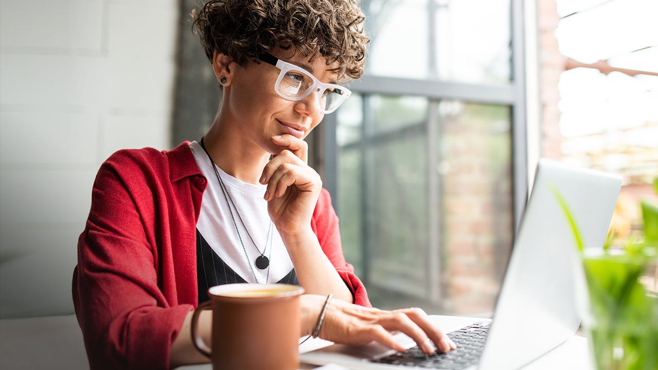 Elegant woman in eyeglasses working on laptop.