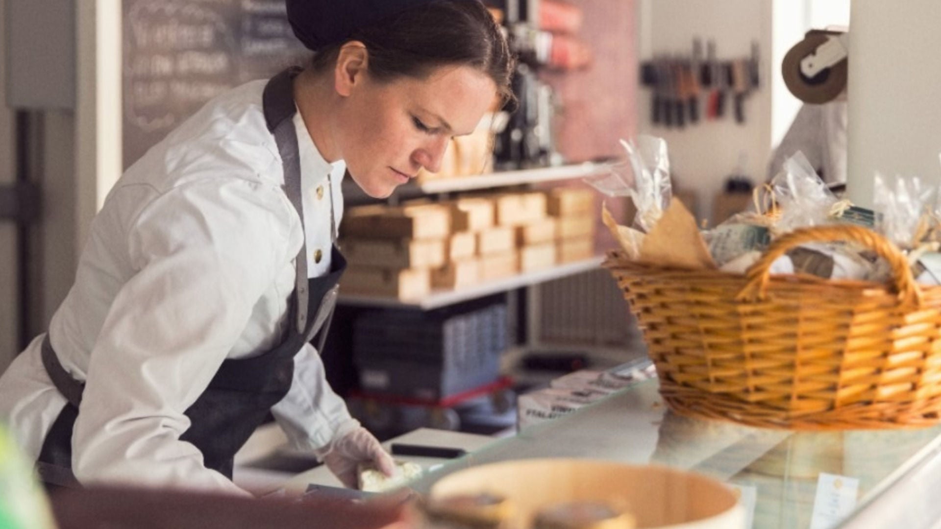 A woman in an apron does paperwork at a counter. 