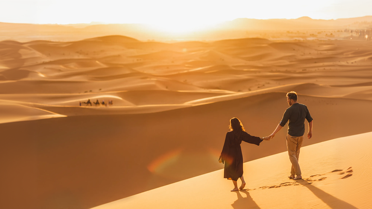 A man and woman walking across a desert