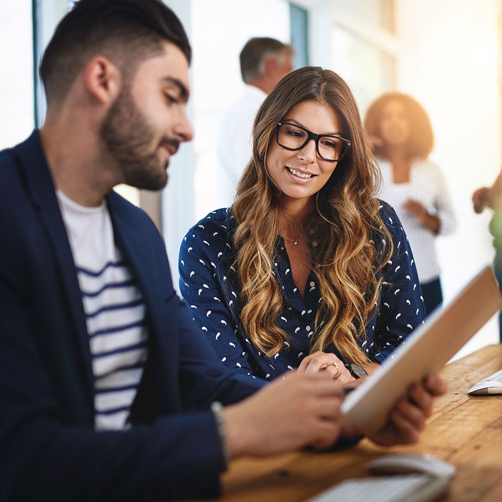 Man and a woman looking over information on a tablet in an office