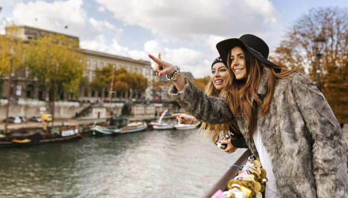 Two female friends looking over a river