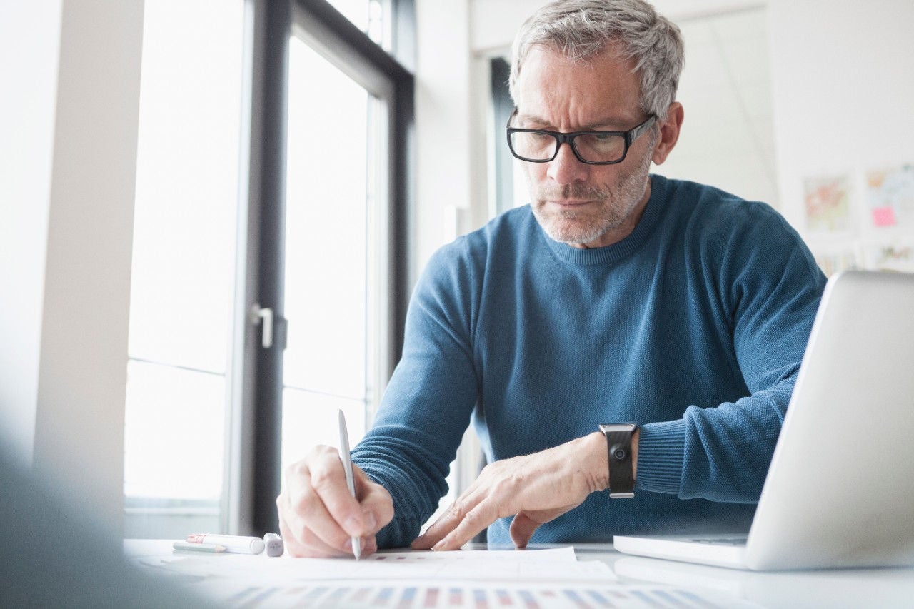 Man sitting in office working with laptop and smart watch