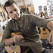 Man replacing strings on guitar.