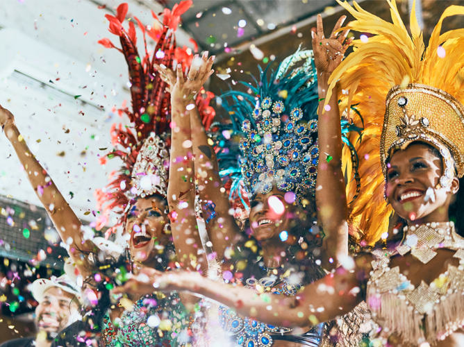 Jubilant samba dancers in dazzling feathered carnival costumes celebrate as confetti falls, capturing the vibrant energy of a parade or festival.
