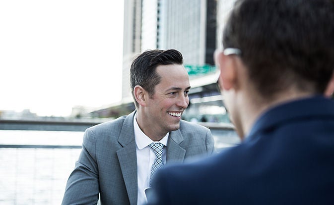 Man smiling during a meeting across a table.