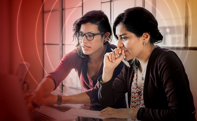 Two ladies are doing someting on laptop