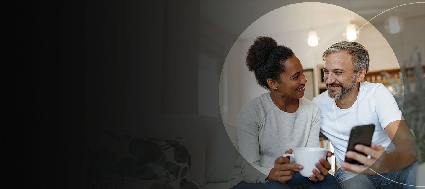 Un homme et une femme regardent un téléphone et sourient.