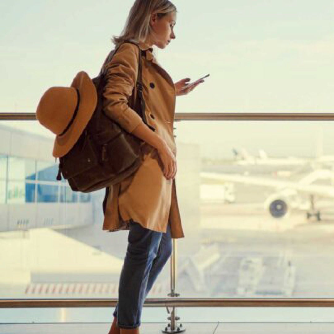 A woman preparing for travel, with luggage and travel gear.