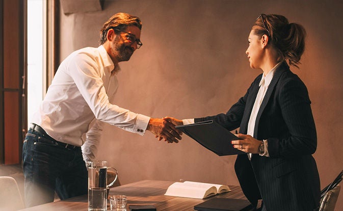 A man and a woman shaking hands while doing business