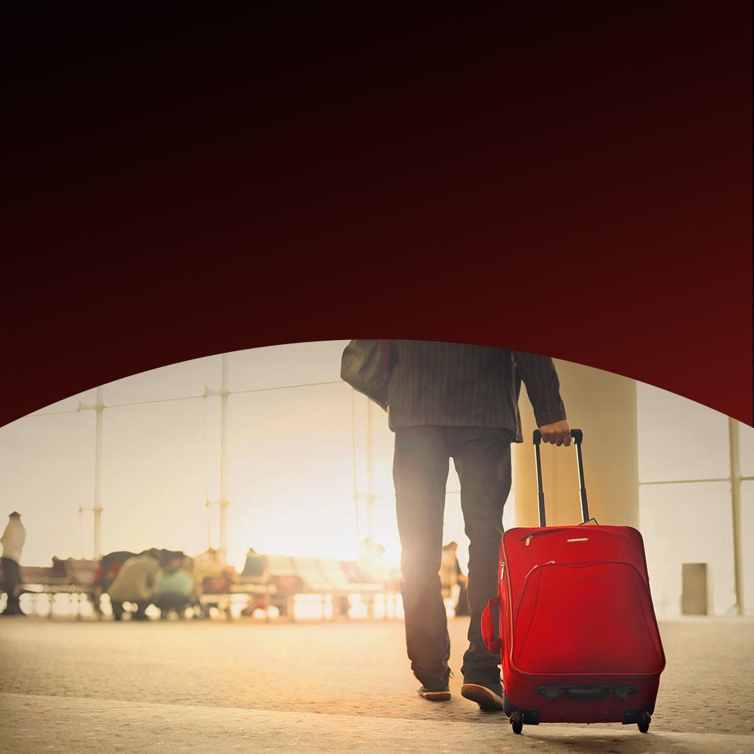 A man stands holding a red suitcase, ready for travel.