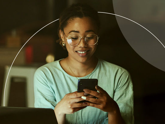 Woman using phone in front of laptop