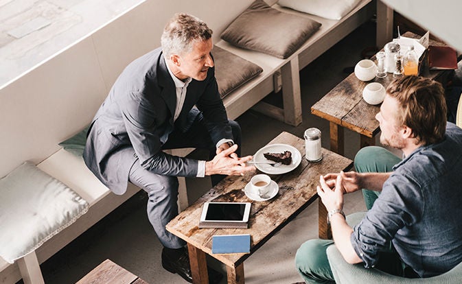 Two people meeting over coffee at a small table.
