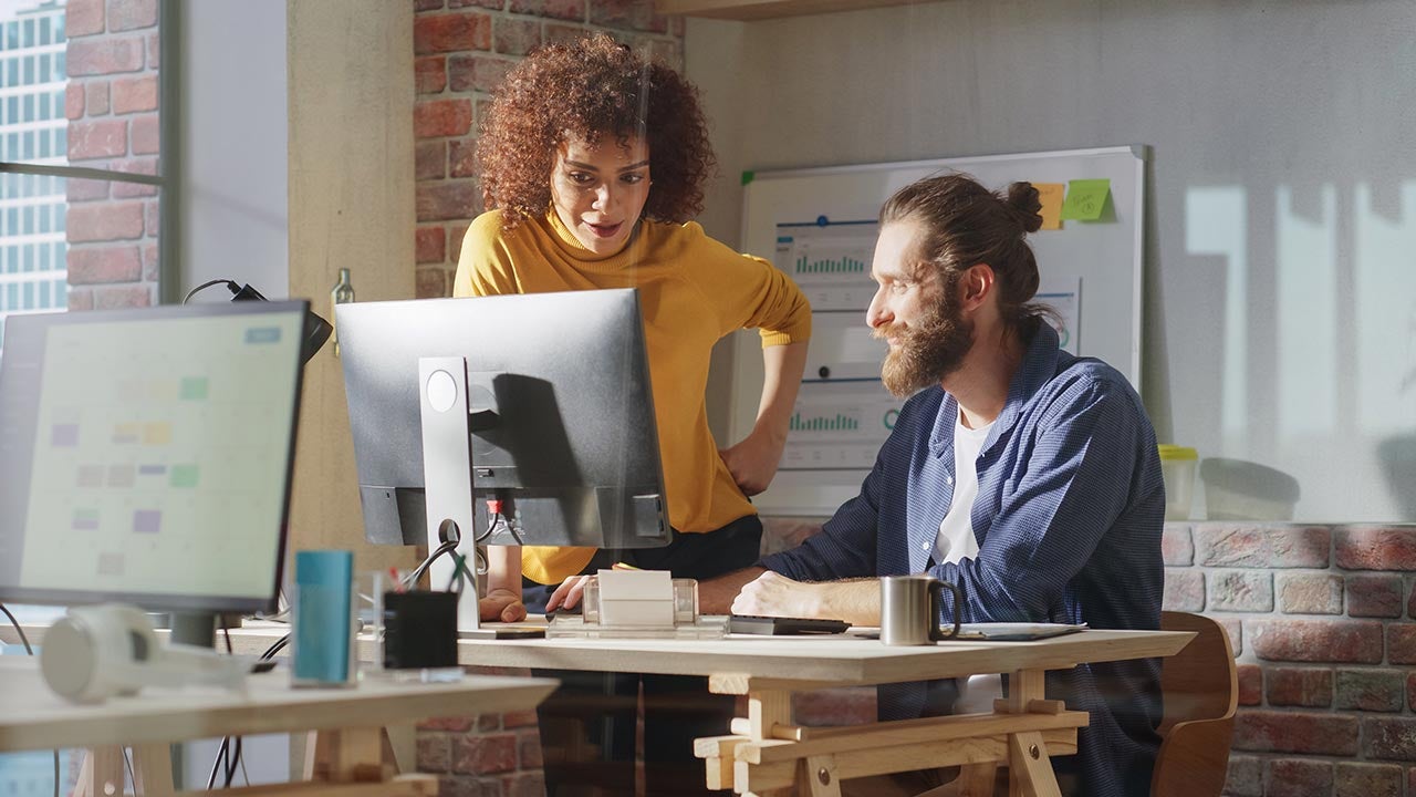 Colleagues planning at computer in office.