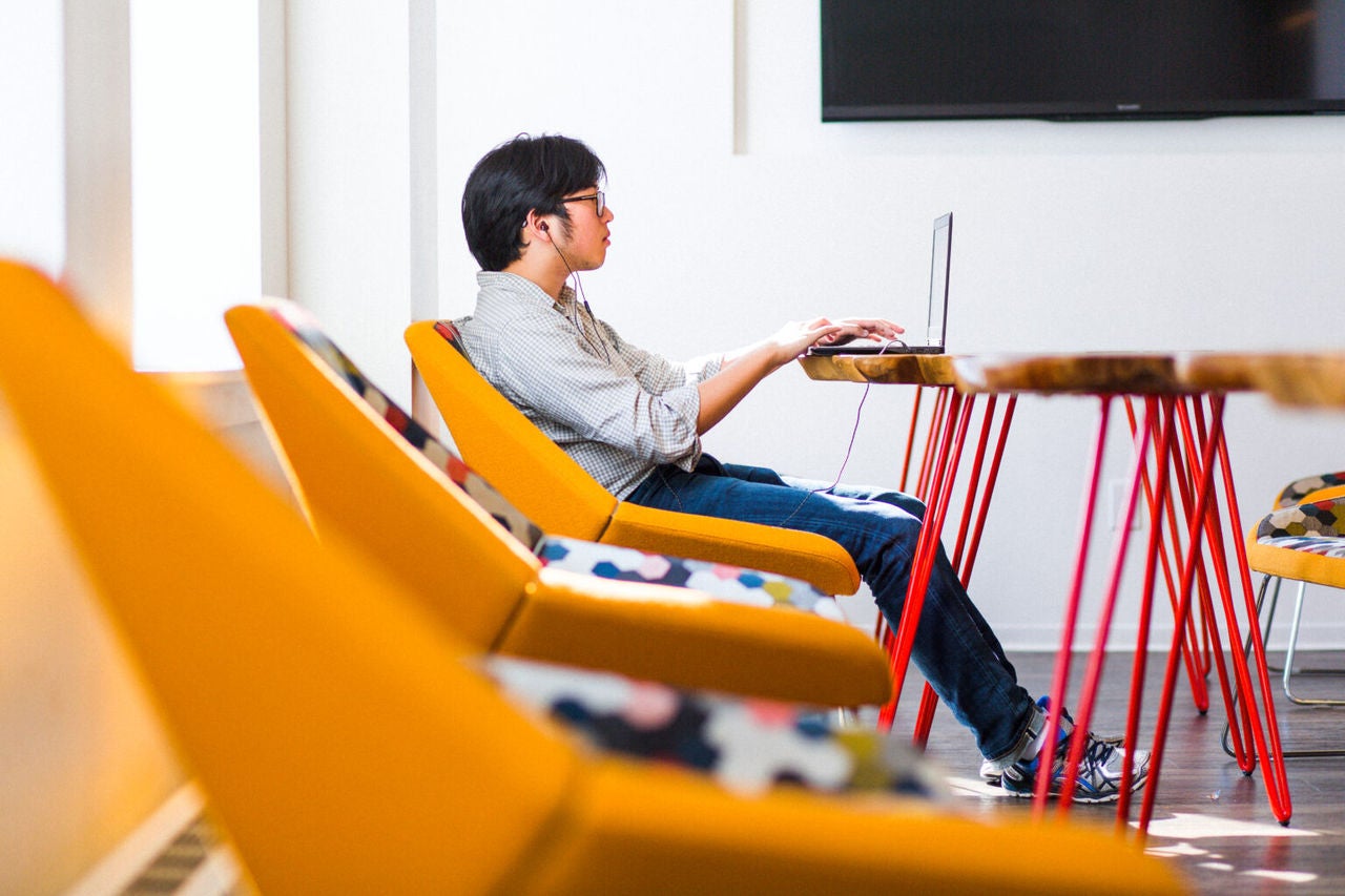 Bărbat la laptop într-un birou open space