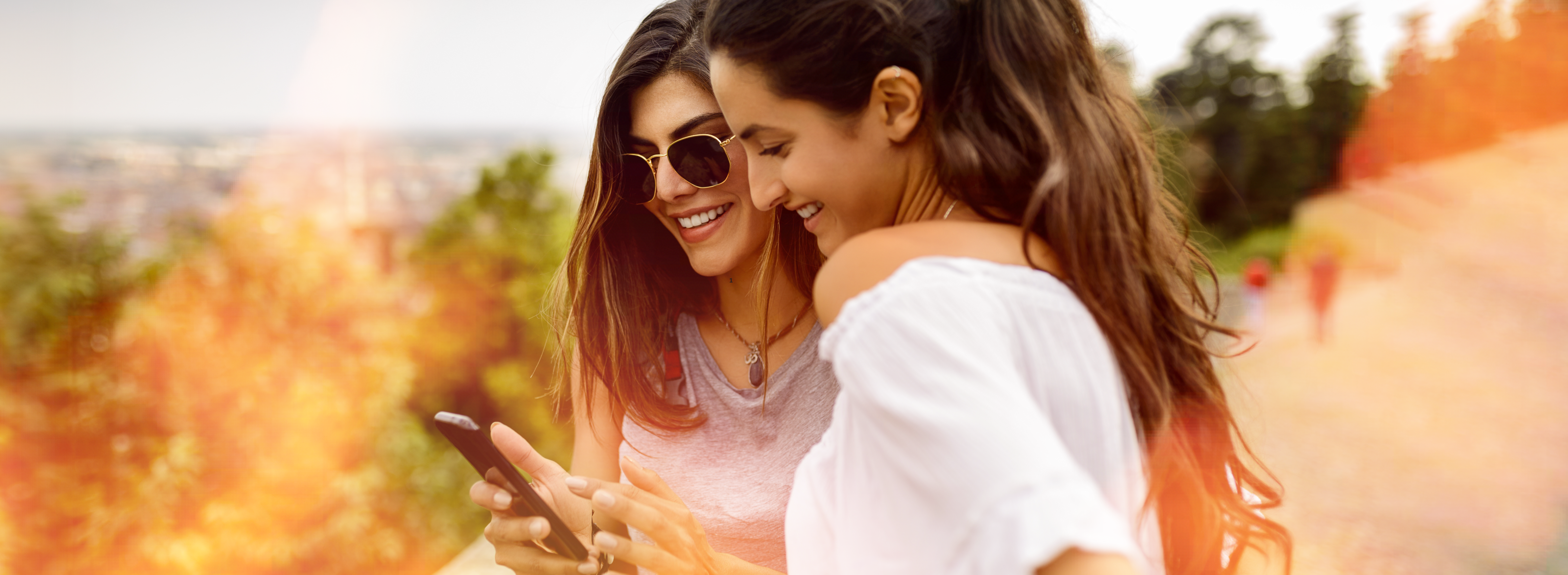 Two women smiling while scrolling phone