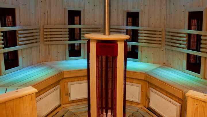 Kör alakú fa szauna belső tér központi fűtőegységgel, fa padokkal és falburkolattal