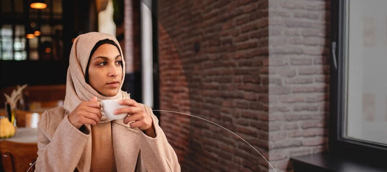 امرأة ترتدي حجابًا تحمل كوب قهوة