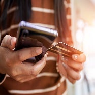 A woman holding a credit card and phone