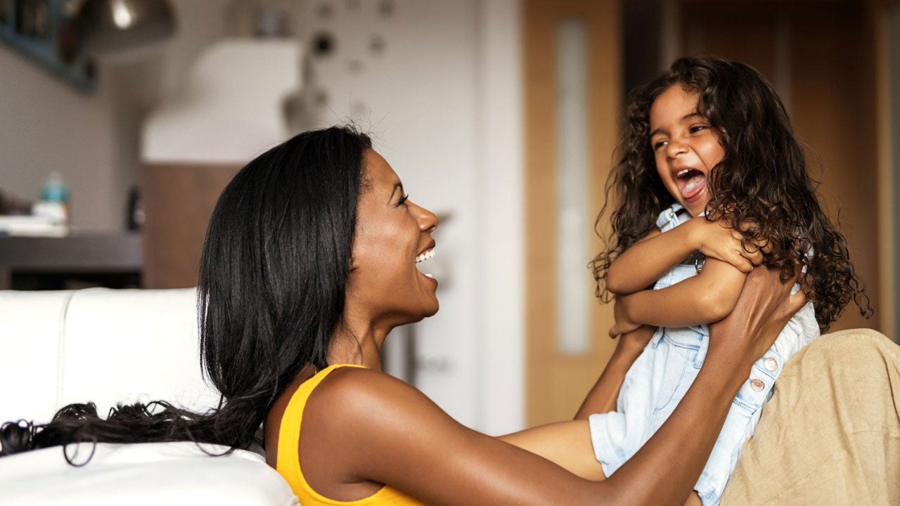 En kvinde og et barn leger og griner sammen.