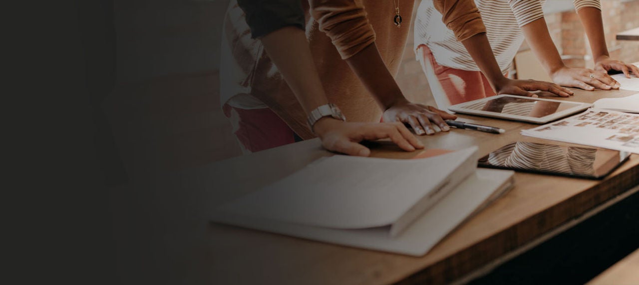 Table with mockups on it and peoples hands.