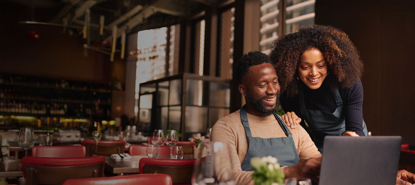 Small business owners using laptop in restaurant