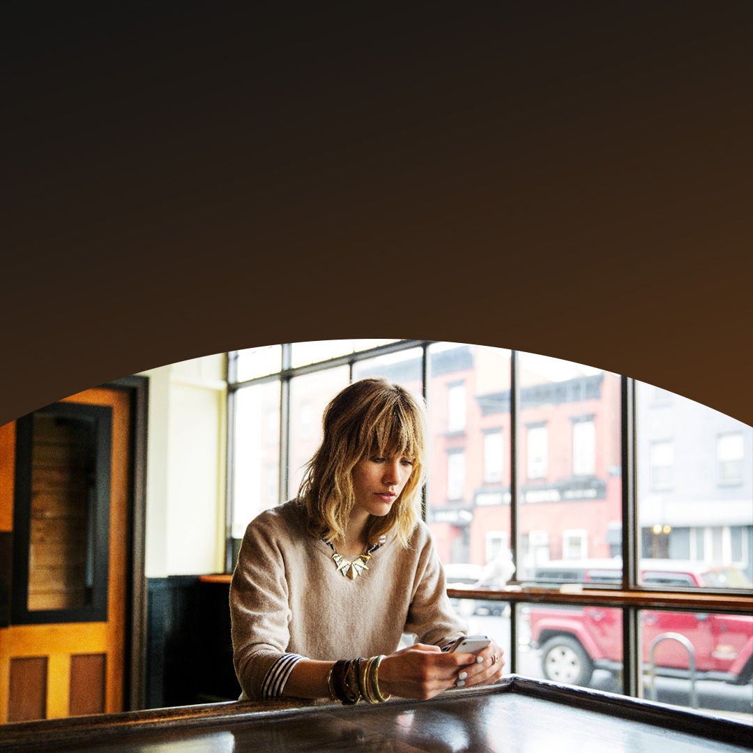A woman on her phone looking out of a cafe window