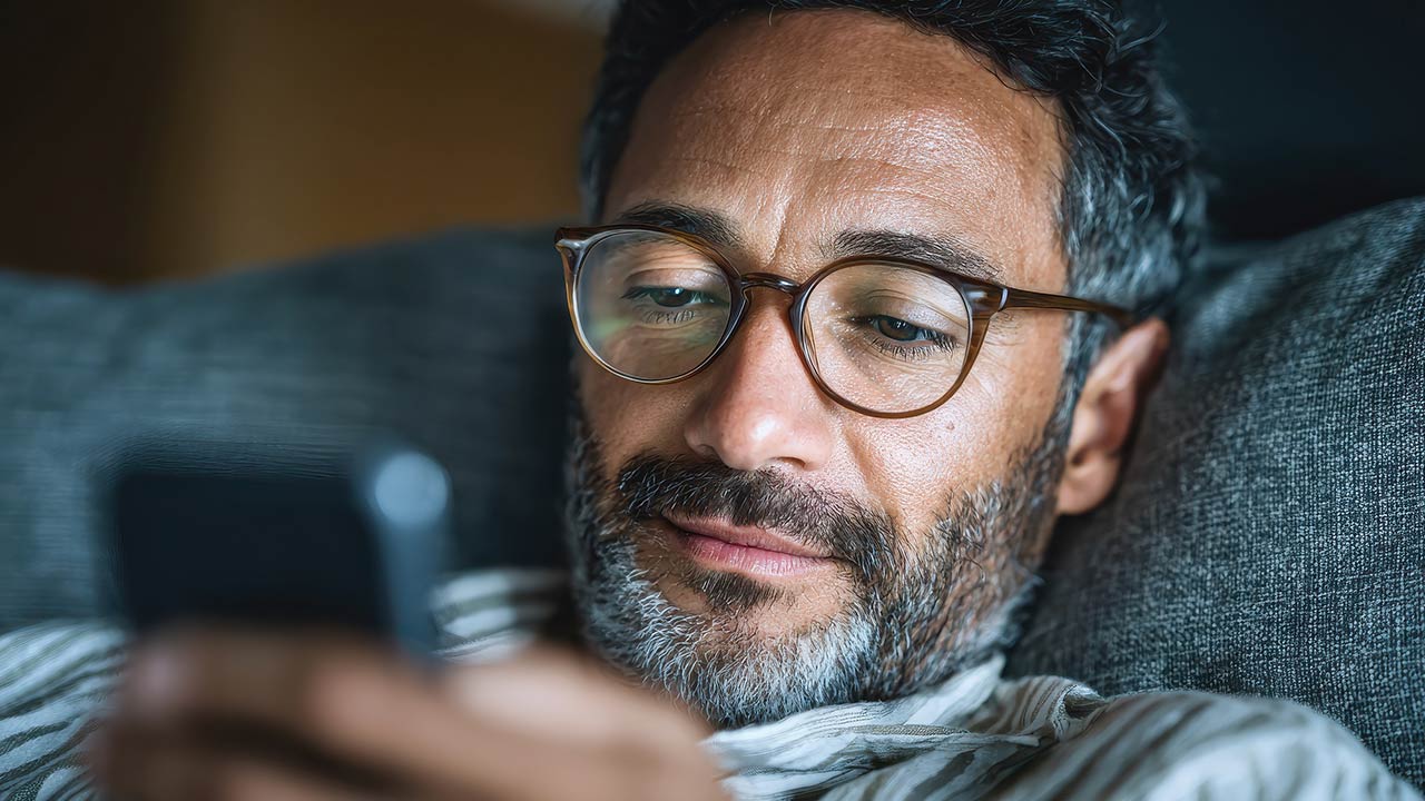 A close up of man's face looking at a phone.