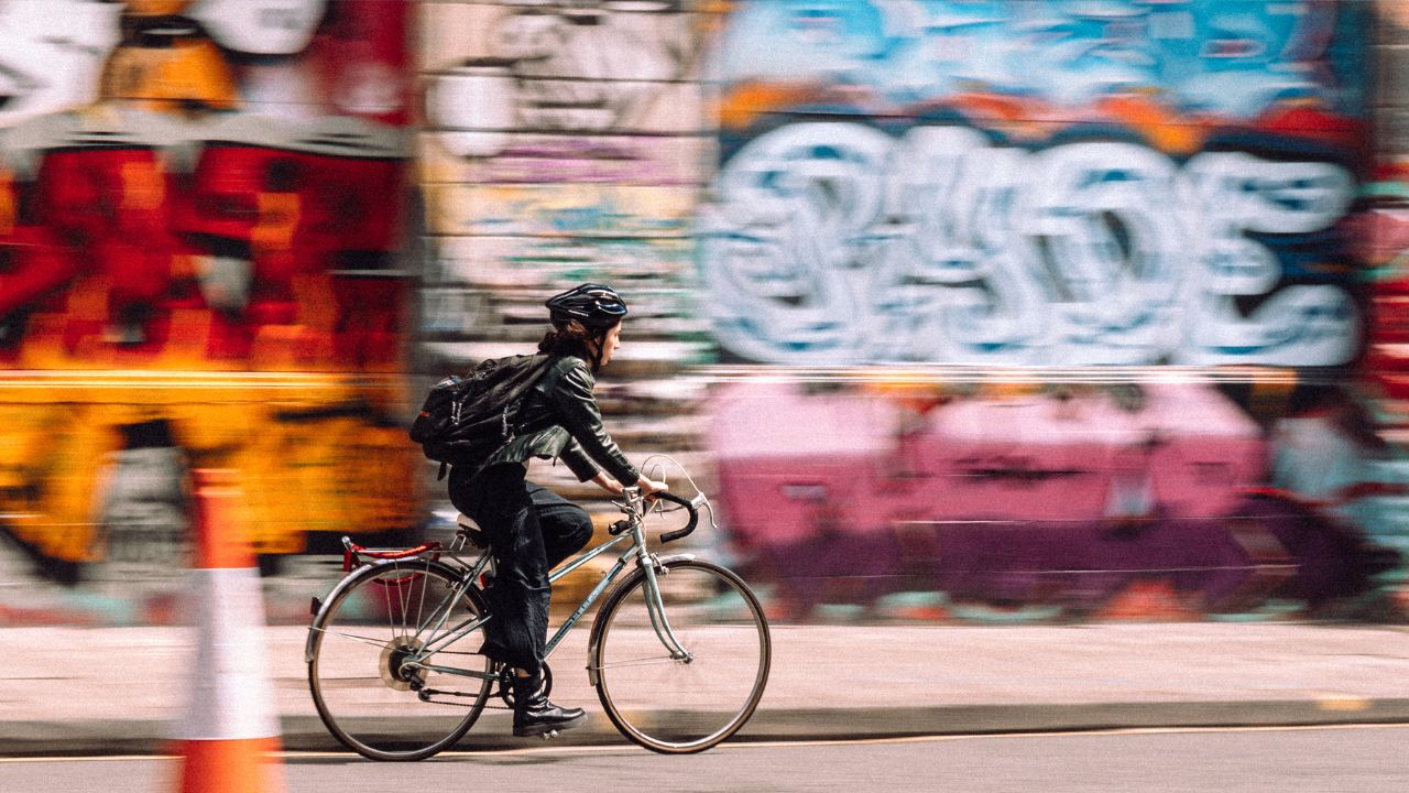 Graffiti on the walls as a woman in a bike rides by in Bristol 