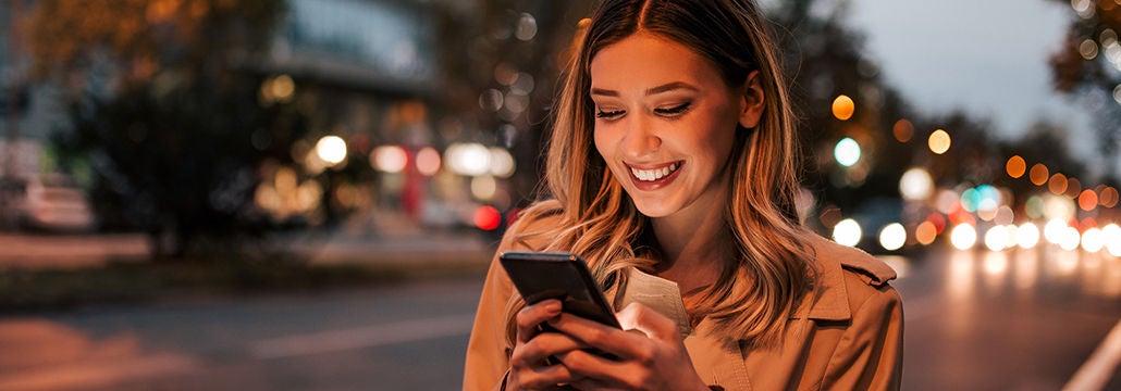 Woman smiling at phone outside in the city