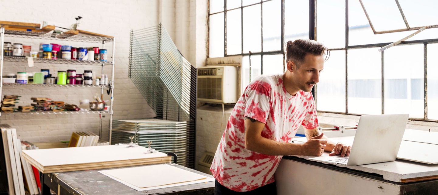 Small business owner using a laptop in a print workshop