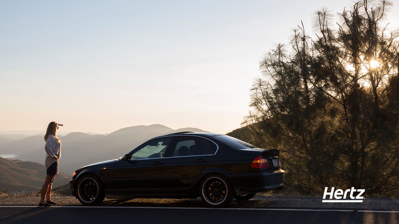 Donna che ammira paesaggio accanto alla sua auto