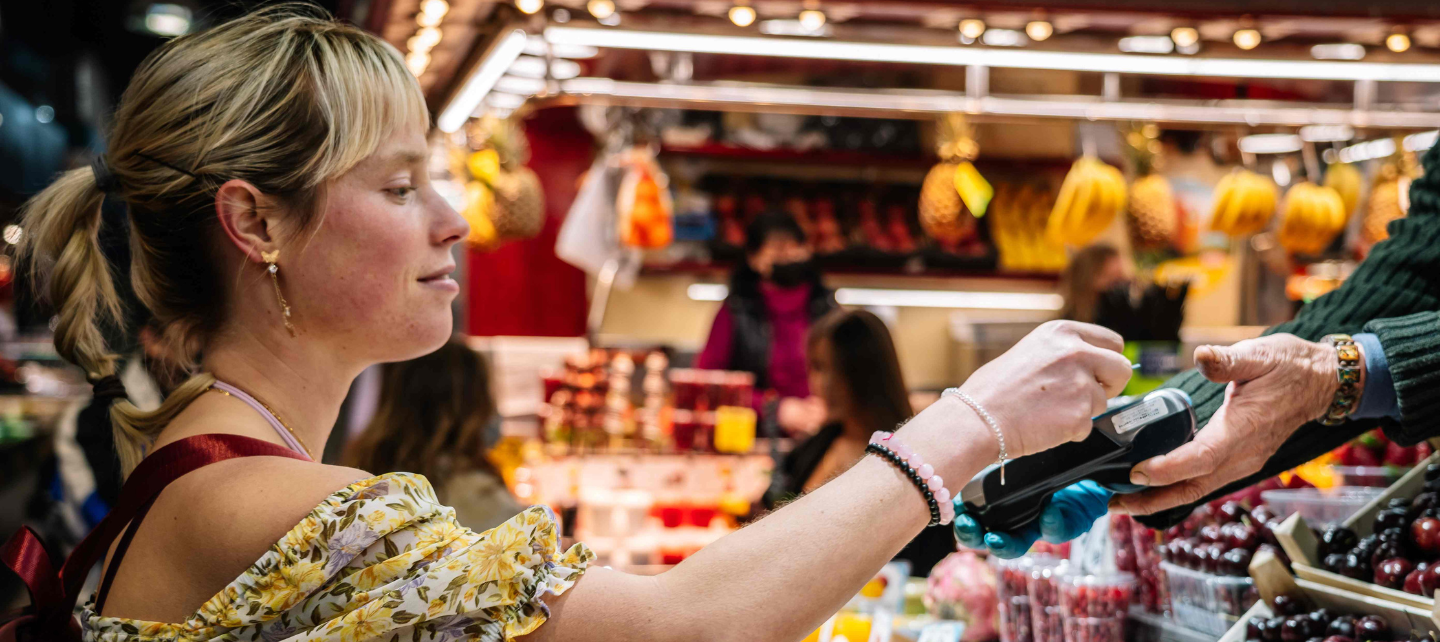 A woman pays for a purchase at Barcelona's food market with a contactless card. 