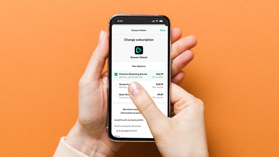 Hands holding a phone changing subscription with orange background.
