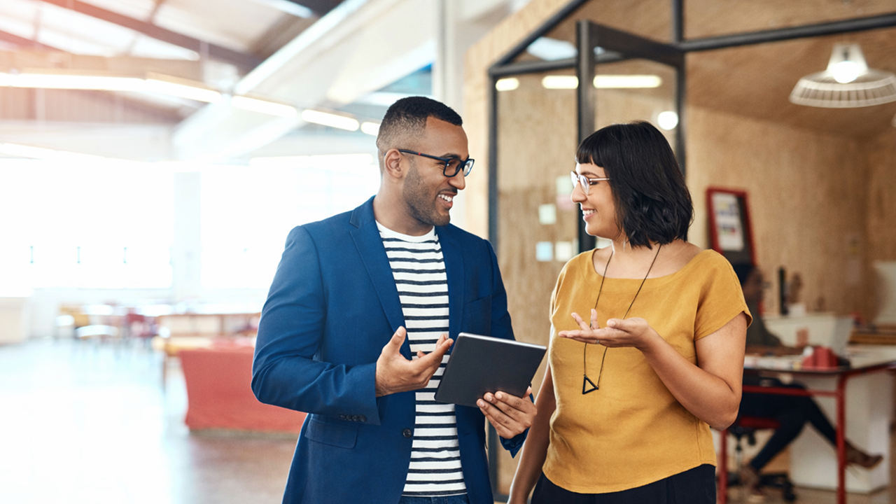 A man and woman talking and holding a tablet